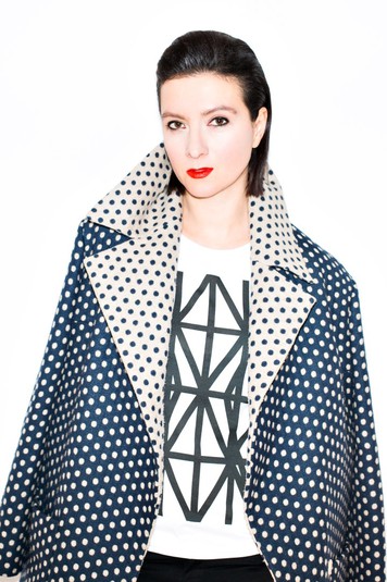 Елена Буренина в футболке Дарьи Кольцовой. Принт Дарьи Кольцовой основывается на ее проекте «Теория защиты», за который она получила Гран-при конкурса молодых художников «МУХи 2015». Оригинальная работа включает аудио, фото и инсталляцию, созданную из стекла и черной изоленты. Изучив архивные фотографии и современные снимки из зоны АТО с изображением окон заклеенных лентой, художница создала выразительный паттерн, воспроизведенный изолентой на стеклах. Люди заклеивают лентой окна в надежде уберечься от осколков, разлетающихся при взрыве стекла от ударной волны. На самом деле это дает очень призрачную надежду на защиту. В адаптации для футболок идею защиты художница переносит в плоскость сексуальных отношений, создавая символ защиты хрупкой человеческой жизни от рискованных связей.