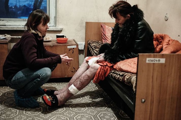 Roza, left, an outreach worker with Club Svitanok, kneels in 2011 across from Katya, 37, who is HIV-positive and struggling with drug addiction, in a Donetsk hospital where she was being treated for pneumonia. Ukraine, 2011.