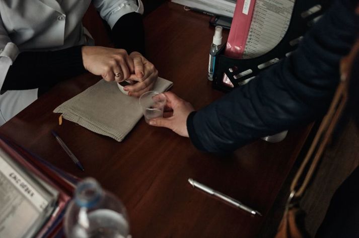 A patient, pictured in 2016, displaced from rebel-controlled areas receives her daily dose of methadone as part of opioid replacement therapy. Her care is managed by Svitanok. Ukraine, 2016.