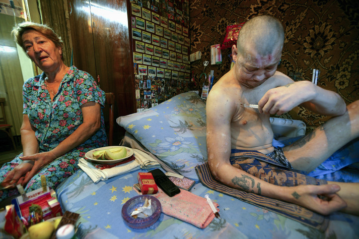 Полтава, 12 августа 2005 г. Живущие на окраине Полтавы, два брата Дима (слева) и Руслан (справа) готовятся уколоть наркотик, пока их мама беспомощно наблюдает за ними. Они наркозависимы уже более двадцати лет, и у них у обоих уже есть дети. Их мать потеряла мужа 15 лет назад и вынуждена была уволиться из садика, где она работала воспитательницей, чтобы присматривать за своими сыновьями, которые употребляют наркотики. Руслан, младший сын, часто ругает ее за то, что она плохая мать, заставляя ее ухаживать за ним и его братом. Ходят слухи, что семья продает наркотики, чтобы братья могли заработать на дозу.