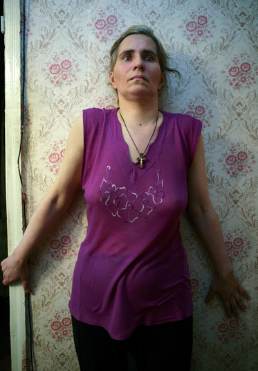 Донецк, 16 августа 2005 г.
Татьяна, 42 года, бывшая наркозависимая, которая начала употреблять наркотики в возрасте 32 лет. Она заразилась ВИЧ в 1996 году и бросила наркотики. У нее двое детей, дочь 23 лет и сын 16 лет. Уже год Татьяна принимает антиретровирусную терапию, но она негативно на нее влияет. Женщина не может нормально ходить, нормально слышать, и ей все время кажется, что как будто что-то внутри гонит ее вперед, управляет ею, поэтому она все время ходит по своей крошечной квартирке. Она не может нормально говорить и постоянно плачет. Мама Татьяны, Ольга, 72 года, заботиться о ней и о ее шестнадцатилетнем сыне. Она делает это из чувства долга, а не из-за любви. Мама Татьяны говорит: «Нужно расстреливать всех наркоманов! Я не понимаю, почему правительство должно тратить деньги на них!». Это ярко иллюстрирует ее непонимание последствий ВИЧ для семьи и общества. Такое непонимание широко распространено в Украине. Это – норма. К ВИЧ-позитивным людям часто относятся, как к преступникам, а не как к жертвам.